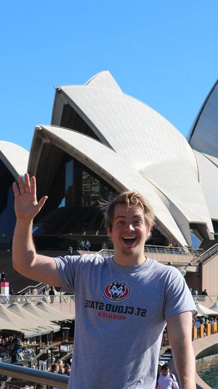 Student waving in front of Sydney Opera House