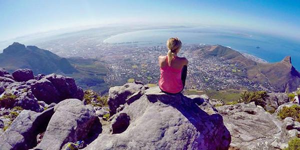 Student sitting on mountain looking into horizon