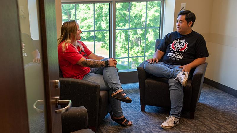 Two people talking in Eastman room